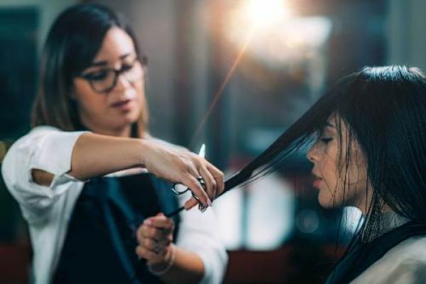 Young beautiful woman getting her hair cut by female hairdresser in beauty salon.